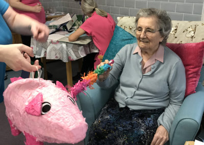 A lady resident hitting a pig-shaped piñata to celebrate Chinese New Year