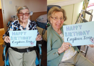 Two St Winifreds Residential Care Home ladies holding a Happy Birthday Captain Tom sign